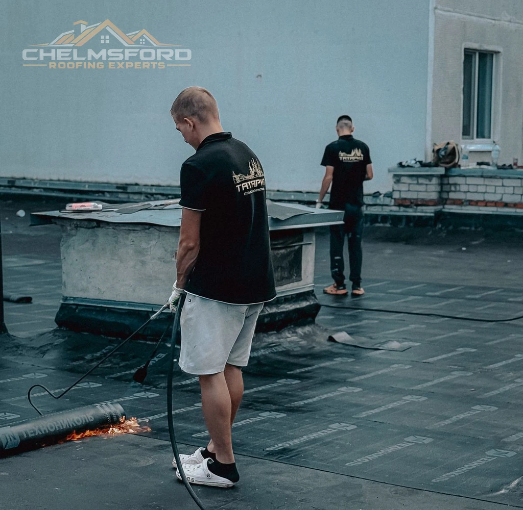 Two roofers installing membrane on a flat roof