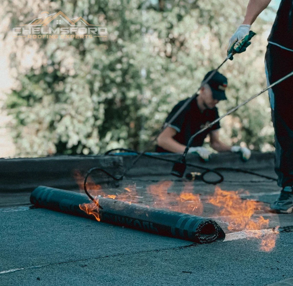 Roofer heating and laying torch-on membrane on a flat roof