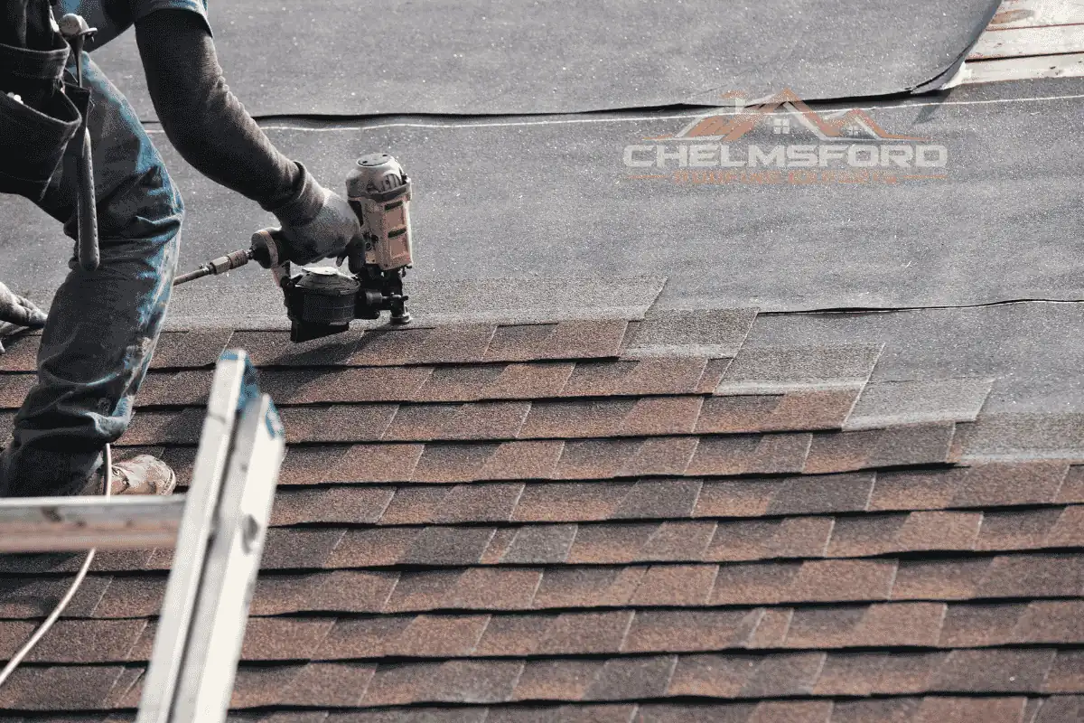 Roofer fixing asphalt shingles with a nail gun